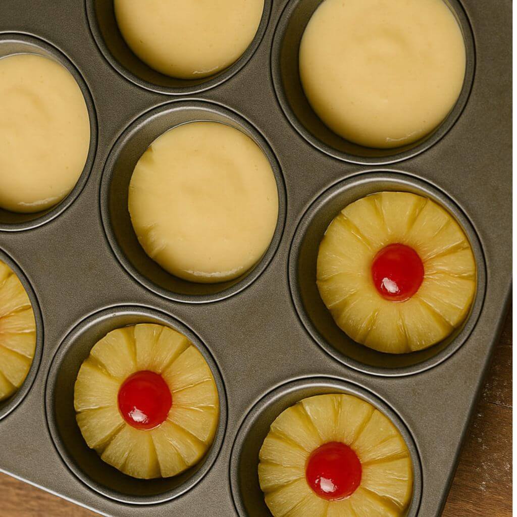 Spoon the batter evenly over the pineapple in each muffin cup