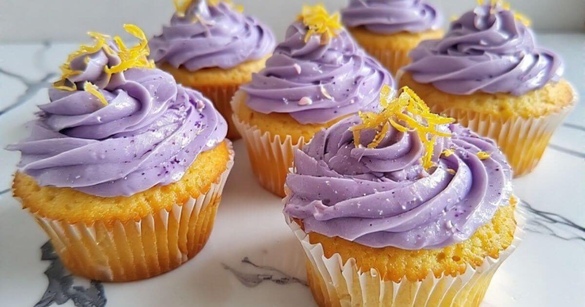 Fluffy lemon lavender cupcakes with pale purple frosting and fresh lemon zest on a white marble surface.