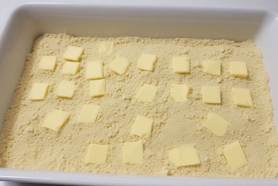 Arrange thin butter slices across the entire cake mix surface