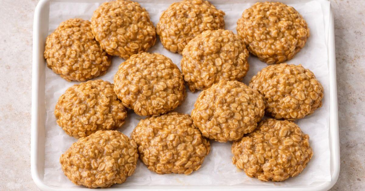 A tray of chewy No Bake Peanut Butter Oatmeal Cookies on white parchment paper, showing the texture of the oats and peanut butter.