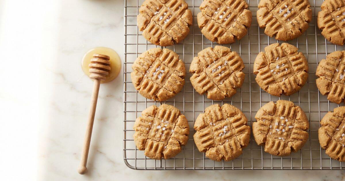 Peanut Butter Honey Cookies cooling on a wire rack, soft and chewy with classic fork crisscross marks and a honey dipper on the side.