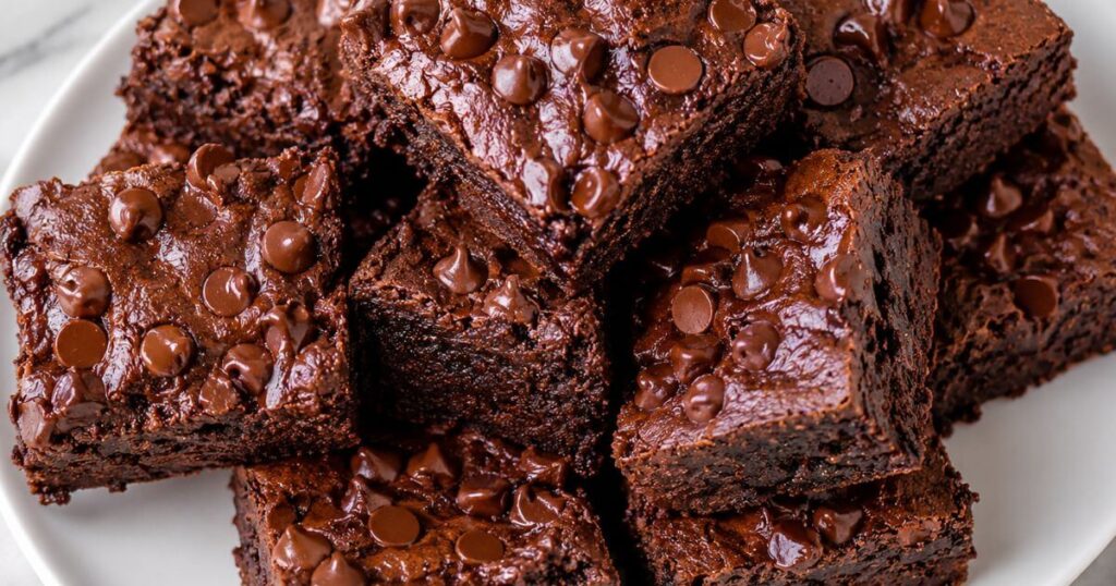 Sweet Potato Brownies stacked on a white plate with fudgy texture and chocolate chips on top