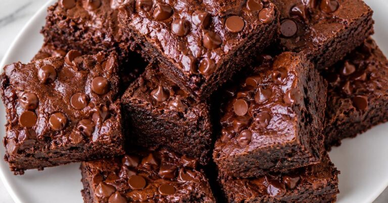 Sweet Potato Brownies stacked on a white plate with fudgy texture and chocolate chips on top